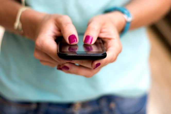 Hands with painted fingernails holding a mobile phone