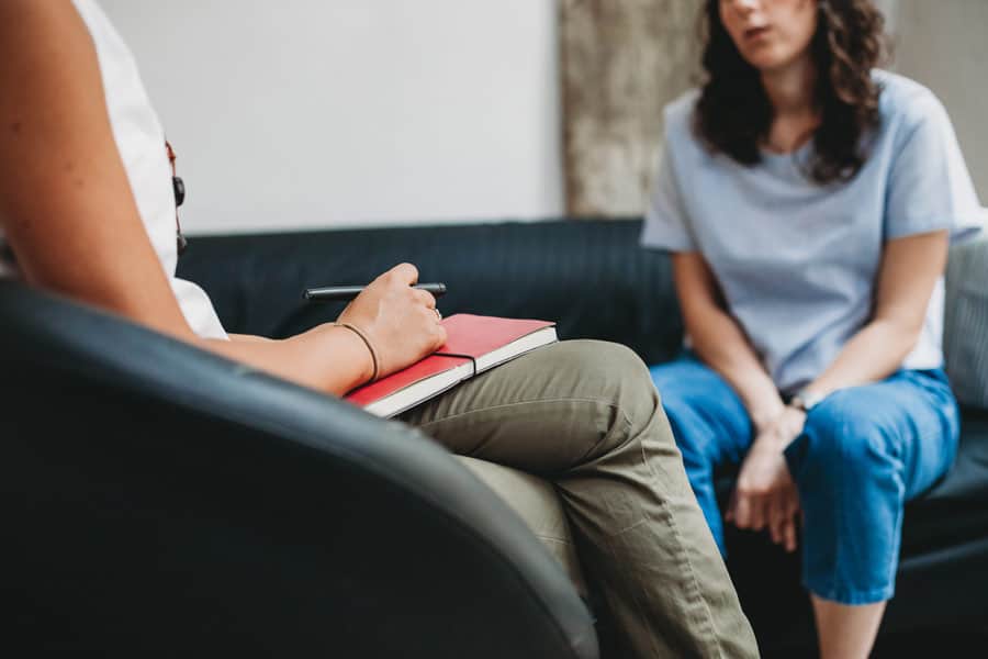 Women partaking in a counselling session, one lady has her hands on a closed notebook